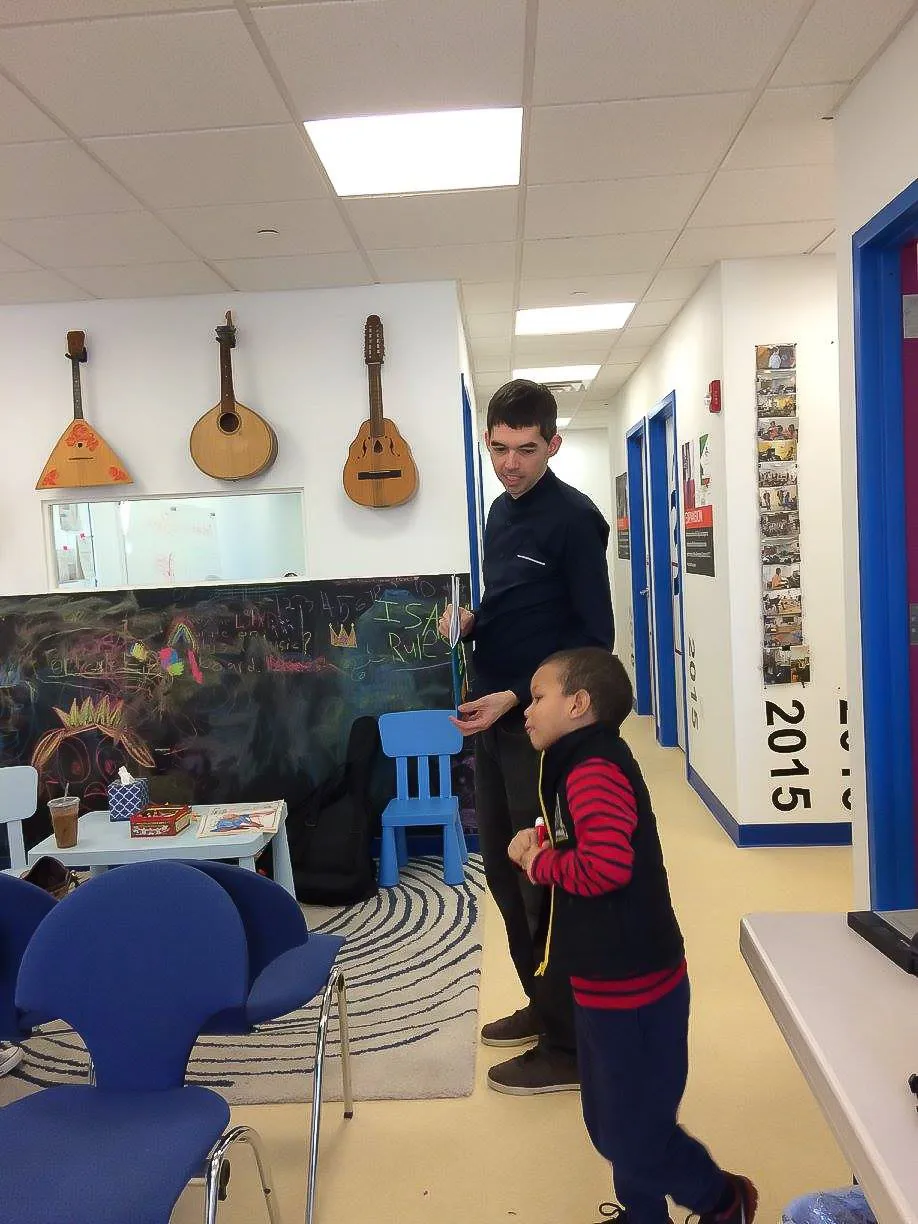 A waiting area with a wall of mandolins and balalaikas, a mural, and child-size blue chairs.